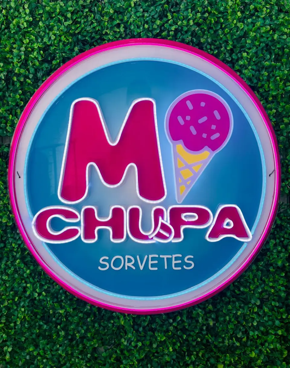 Logo circular da M Chupa Sorvetes em neon LED rosa e azul