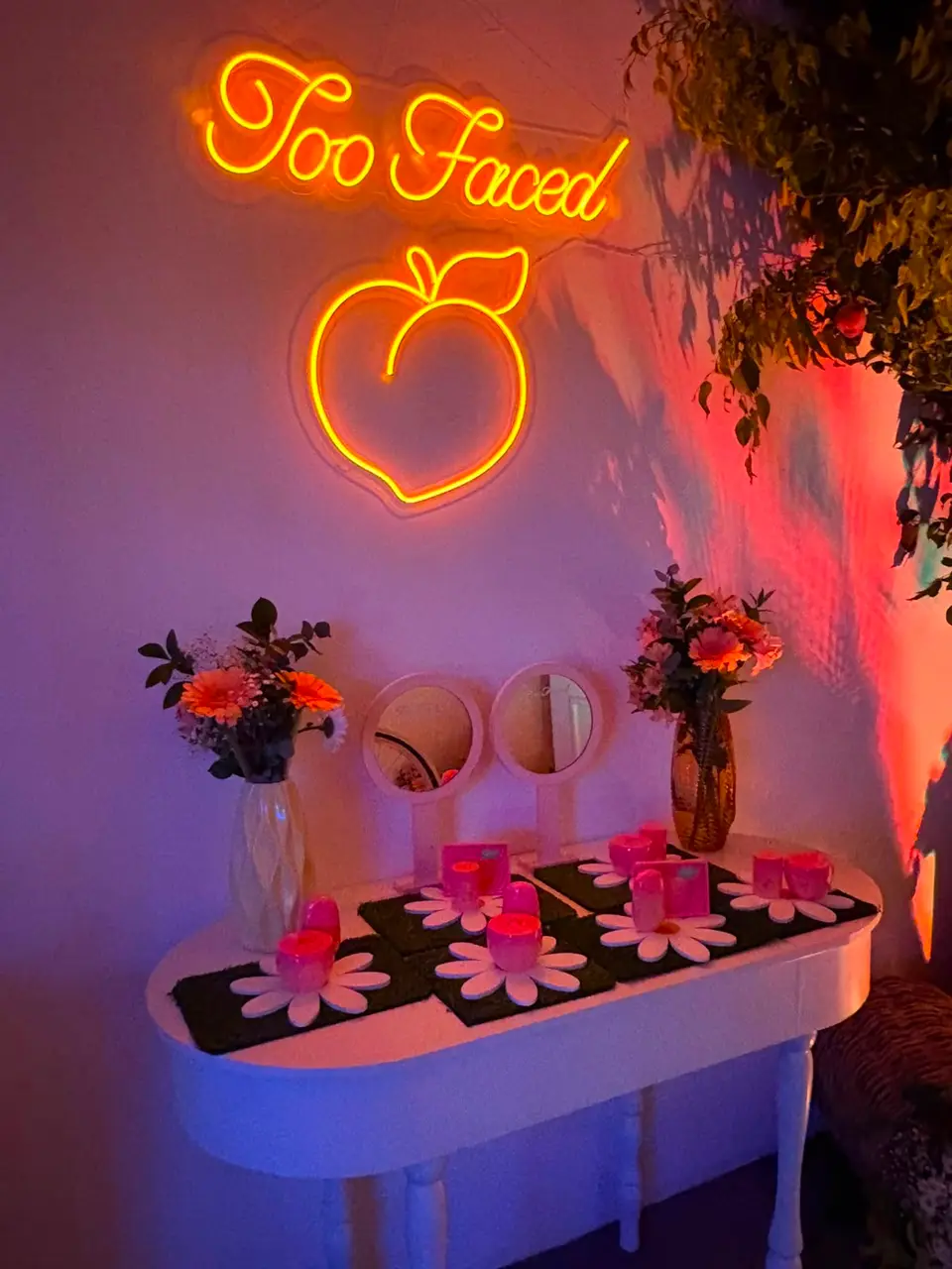 Mesa decorada com flores e painel neon LED em pêssego